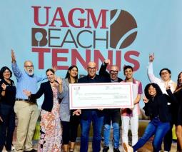 grupo de facultad y estudiantes celebrando con cheque de la actividad de UAGM Beach Tennis Open