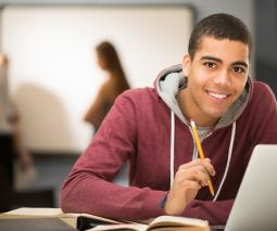 foto de estudiante con una laptop mirando a cámara