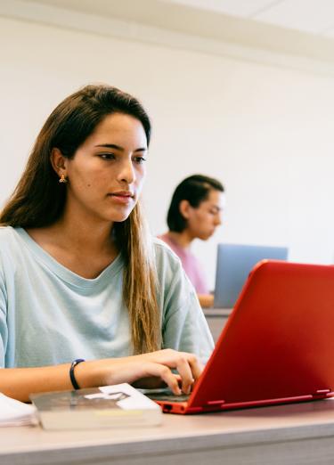 Foto de estudiante en un salon con una computadora