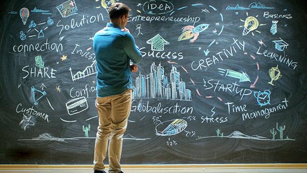 Persona parada mirando una pizarra con muchos apuntes