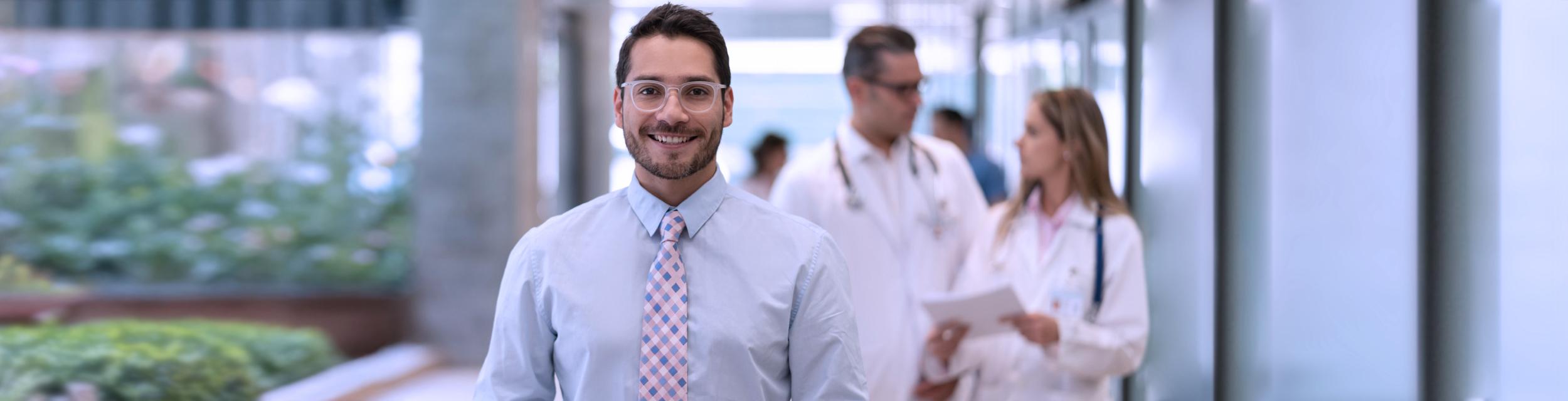 Hombre caminando por pasillo y dos profesionales de la salud al fondo