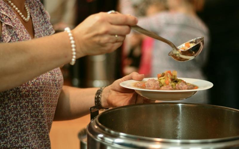 cocinera con olla en la mano repartiendo comida