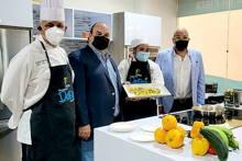 4 personas paradas frente a una cocina mostrando un plato recién confeccionado