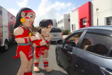 Imagen del taíno y la taína, las mascotas de la UAGM, saludando a un carro que está pasando