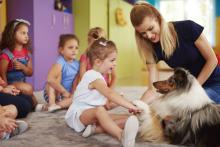 niños pequeños con perro y maestra 